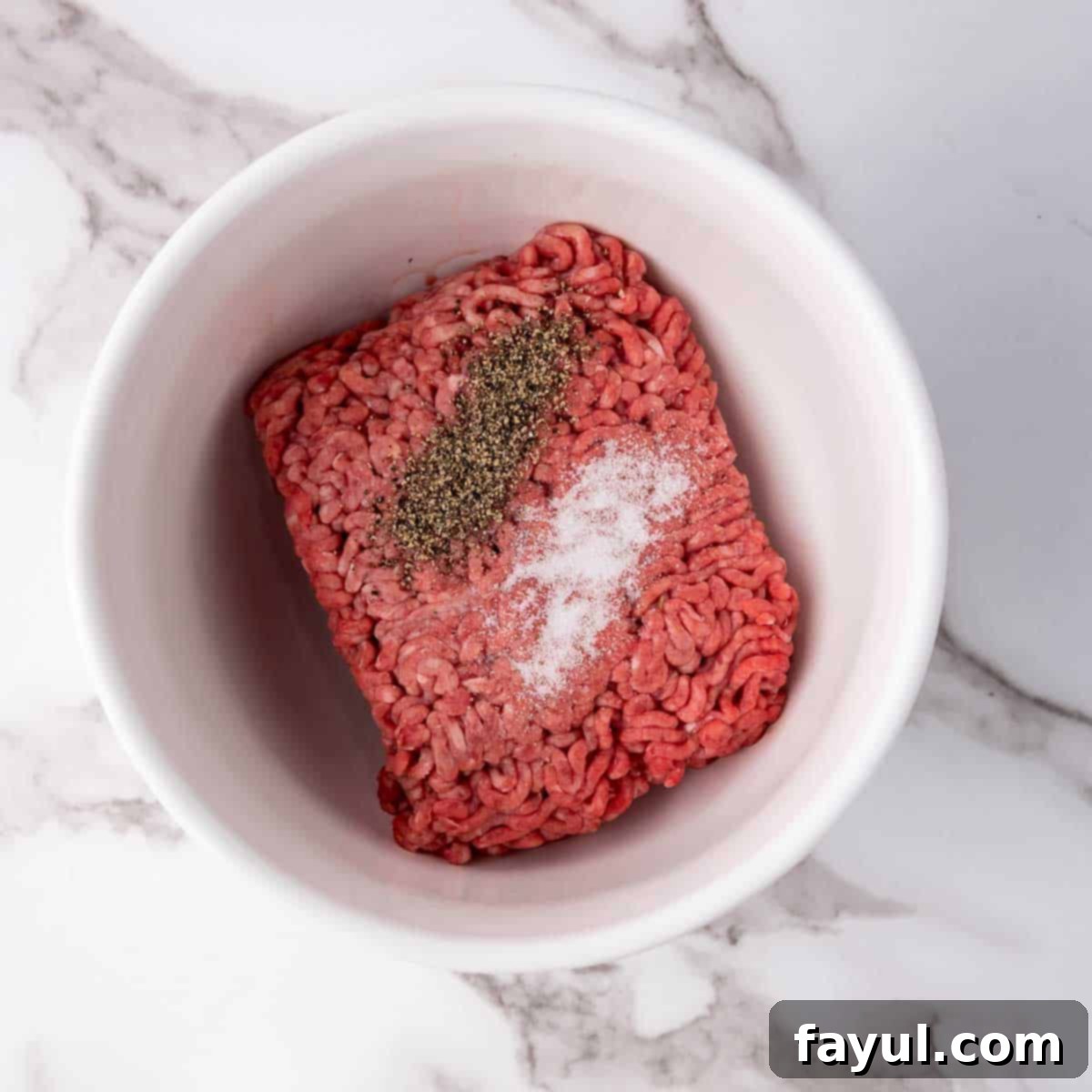 Overhead view of process shot 1 - first, combine the ground beef with salt and pepper.