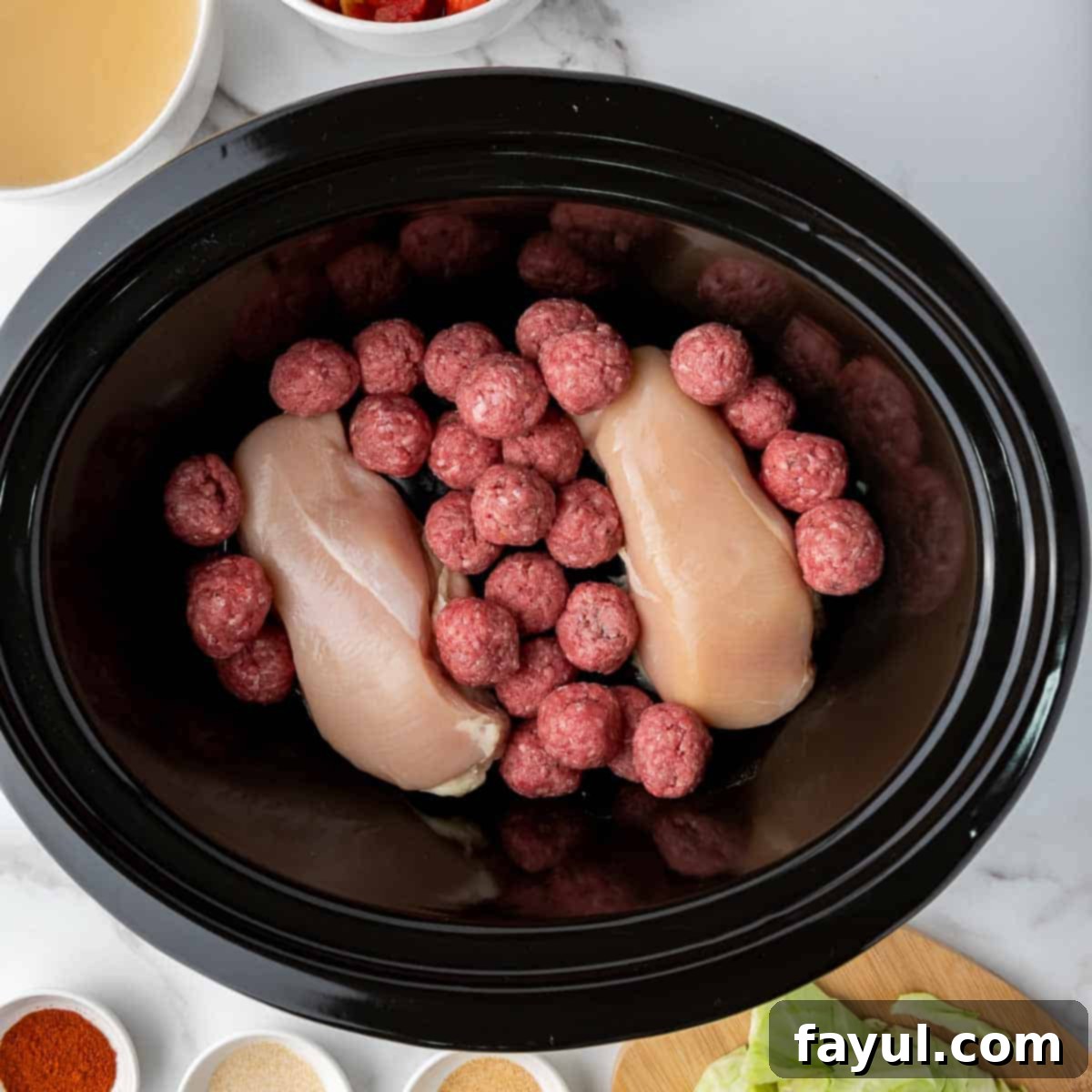 Overhead view of process shot 4 - combine the chicken breast and meatballs in the slow cooker.