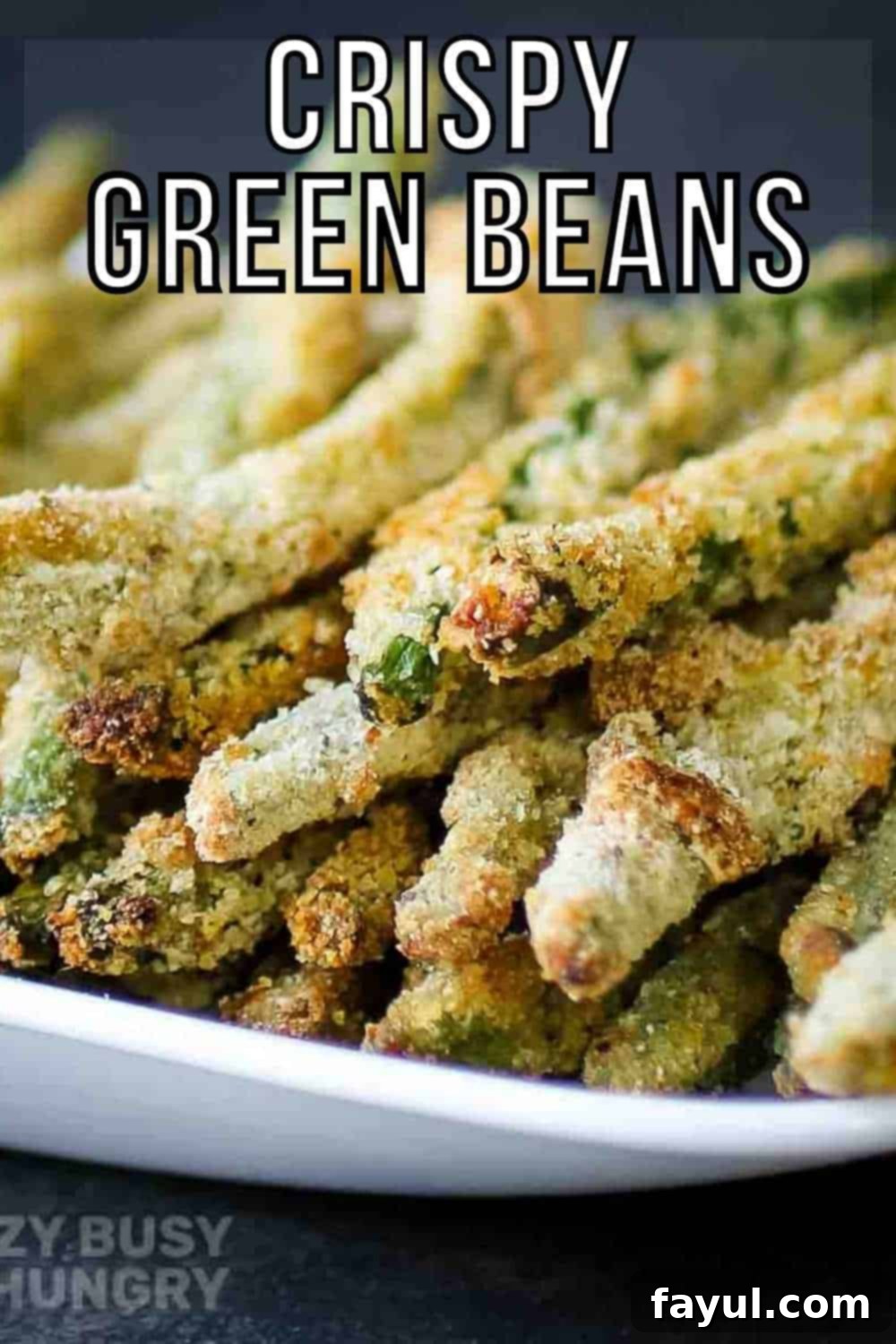 Stacked crispy baked green bean fries on a white plate with a black background, showcasing their golden-brown, crunchy texture.