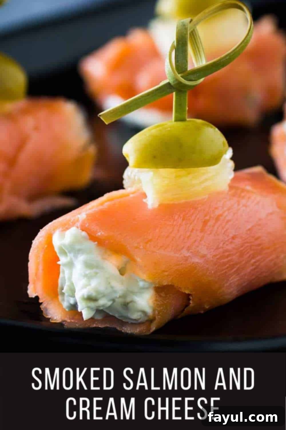 Close up shot of multiple smoked salmon and cream cheese bites, elegantly rolled and topped with lemon and olive, on a sleek black plate, ready to be served.