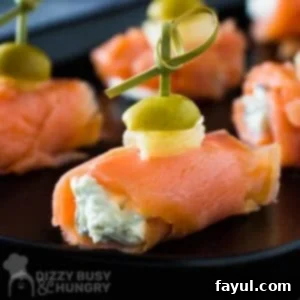 Side view of multiple smoked salmon and cream cheese bites, neatly arranged on a black plate, showcasing their elegant presentation and delightful texture.