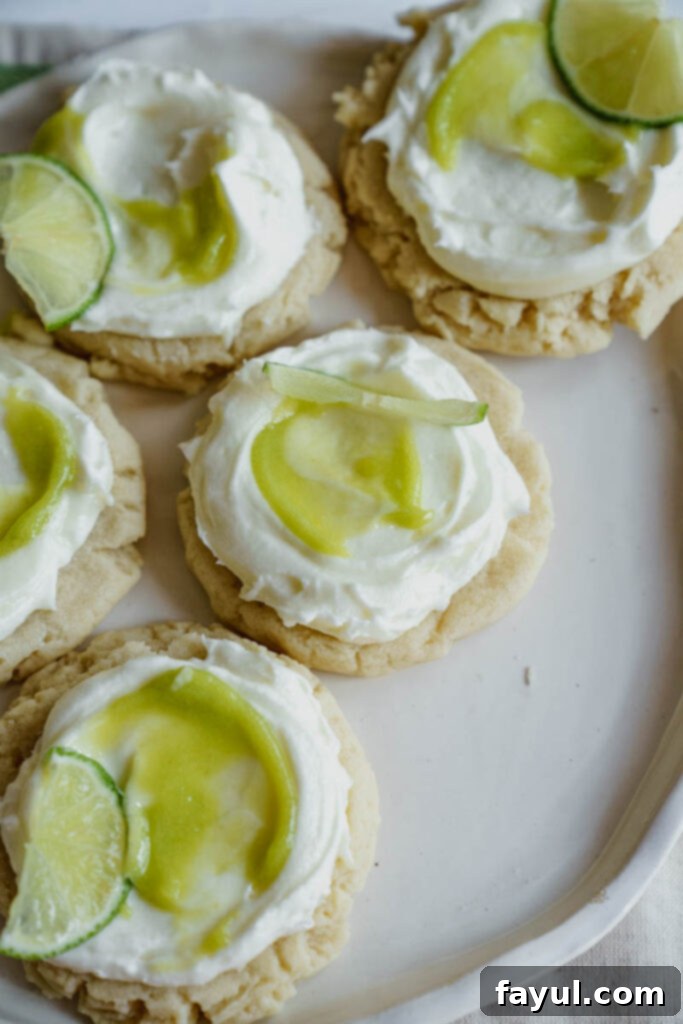 Two hands holding a frosted coconut lime sugar cookie