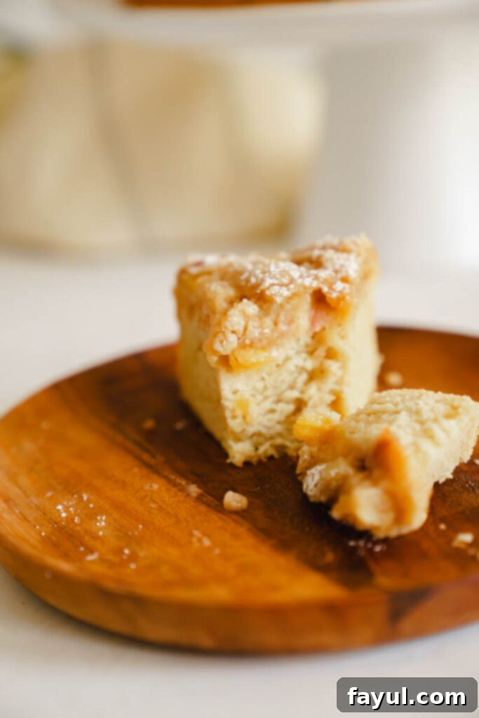 A slice of peach cobbler cake on a plate, showing the layers