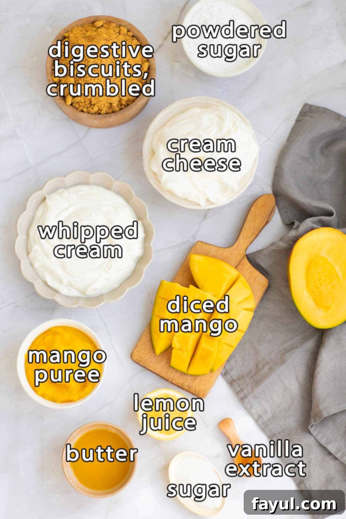 Velvet Mango No-Bake Delight 3 Overhead shot of ingredients - digestive biscuits crumbled, powdered sugar, cream cheese, whipped cream, diced mango, mango puree, butter, lemon juice, sugar, and vanilla extract.