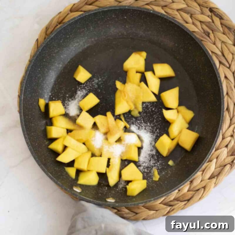Velvet Mango No-Bake Delight 8 Overhead view of process shot 5 - in a saucepan, combine the diced mango, sugar, and lemon juice. Cook until the mango is softened and the sugar is dissolved.