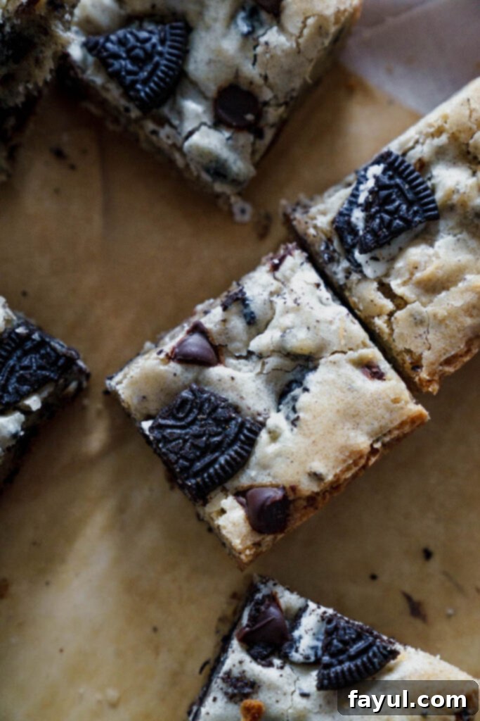 Two hands holding a piece of Oreo Blondie, showcasing the chewy texture and visible Oreo chunks.