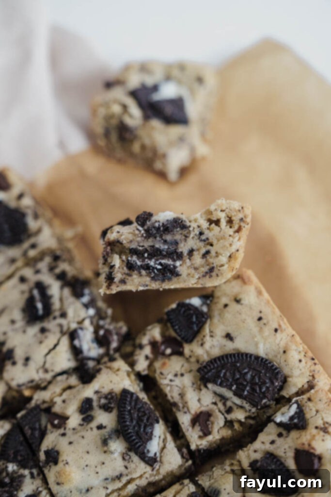 A slice of Oreo Blondie with a bite taken, showing the gooey interior.