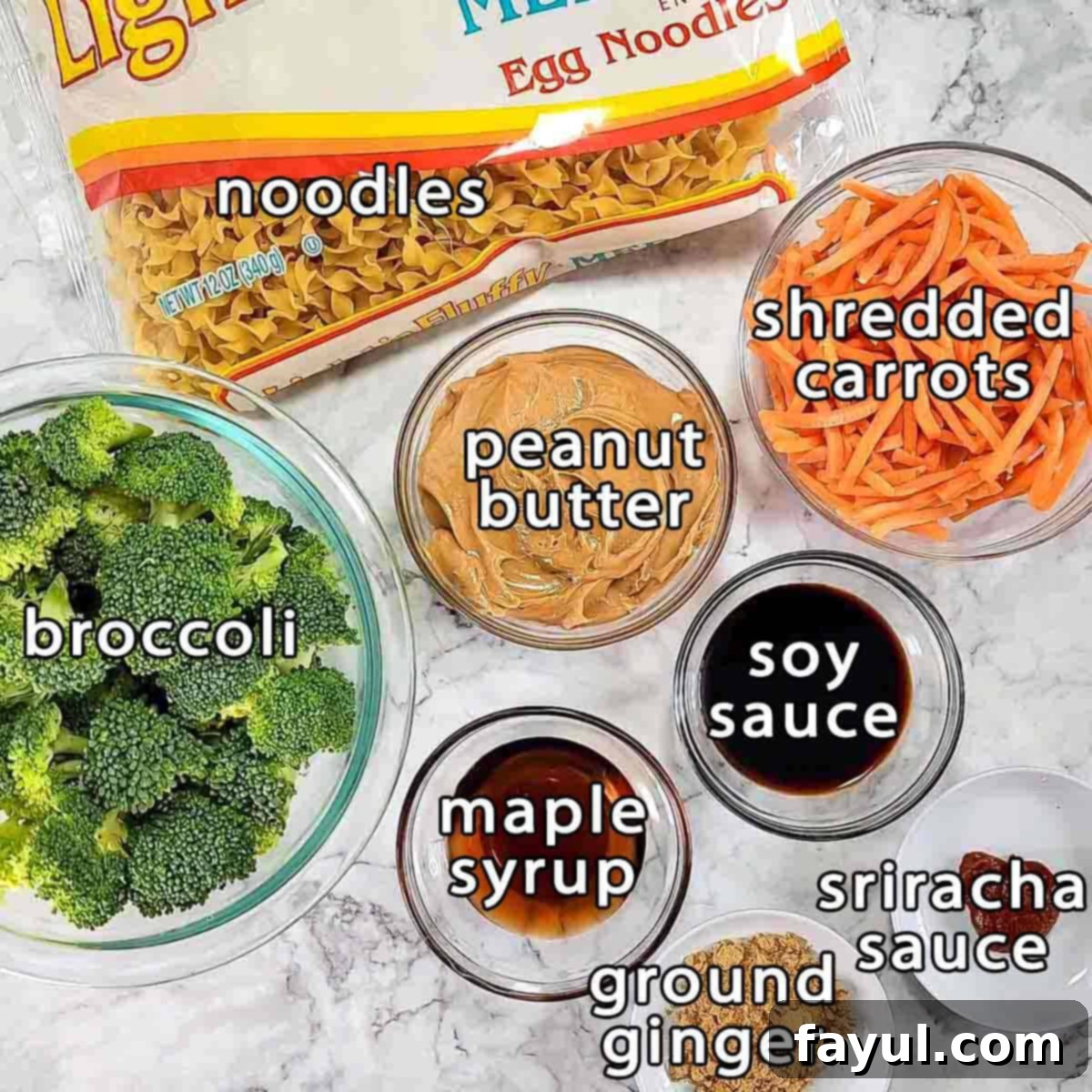 Overhead shot of ingredients - noodles, broccoli, shredded carrots, peanut butter, soy sauce, maple syrup, sriracha sauce, and ground ginger.