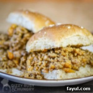 Side view of two homemade sloppy joe sliders on a white plate, highlighting the delicious filling.