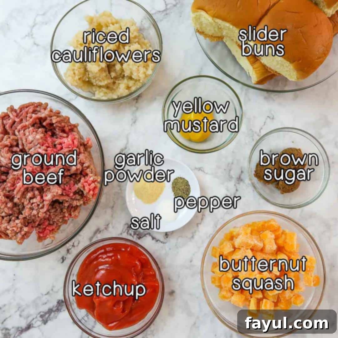 Overhead shot of all the key ingredients laid out: ground beef, riced cauliflower, yellow mustard, ketchup, brown sugar, butternut squash, garlic powder, pepper, salt, and slider buns on a white surface.