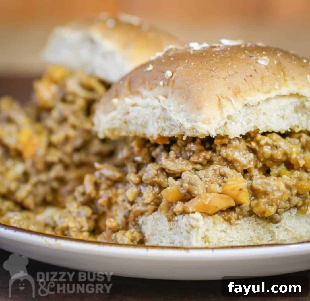 Side shot of two beautifully plated sloppy joe sliders on a white plate, highlighting the fluffy bun and saucy filling.