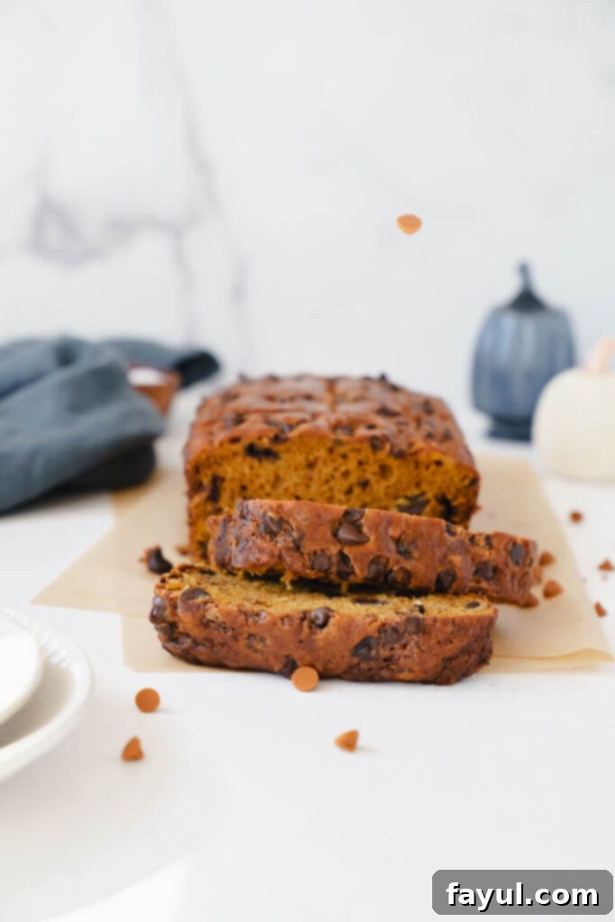 A selection of key ingredients for making pumpkin chocolate chip bread, neatly arranged on a wooden surface, including pumpkin puree, various spices, and chocolate chips.