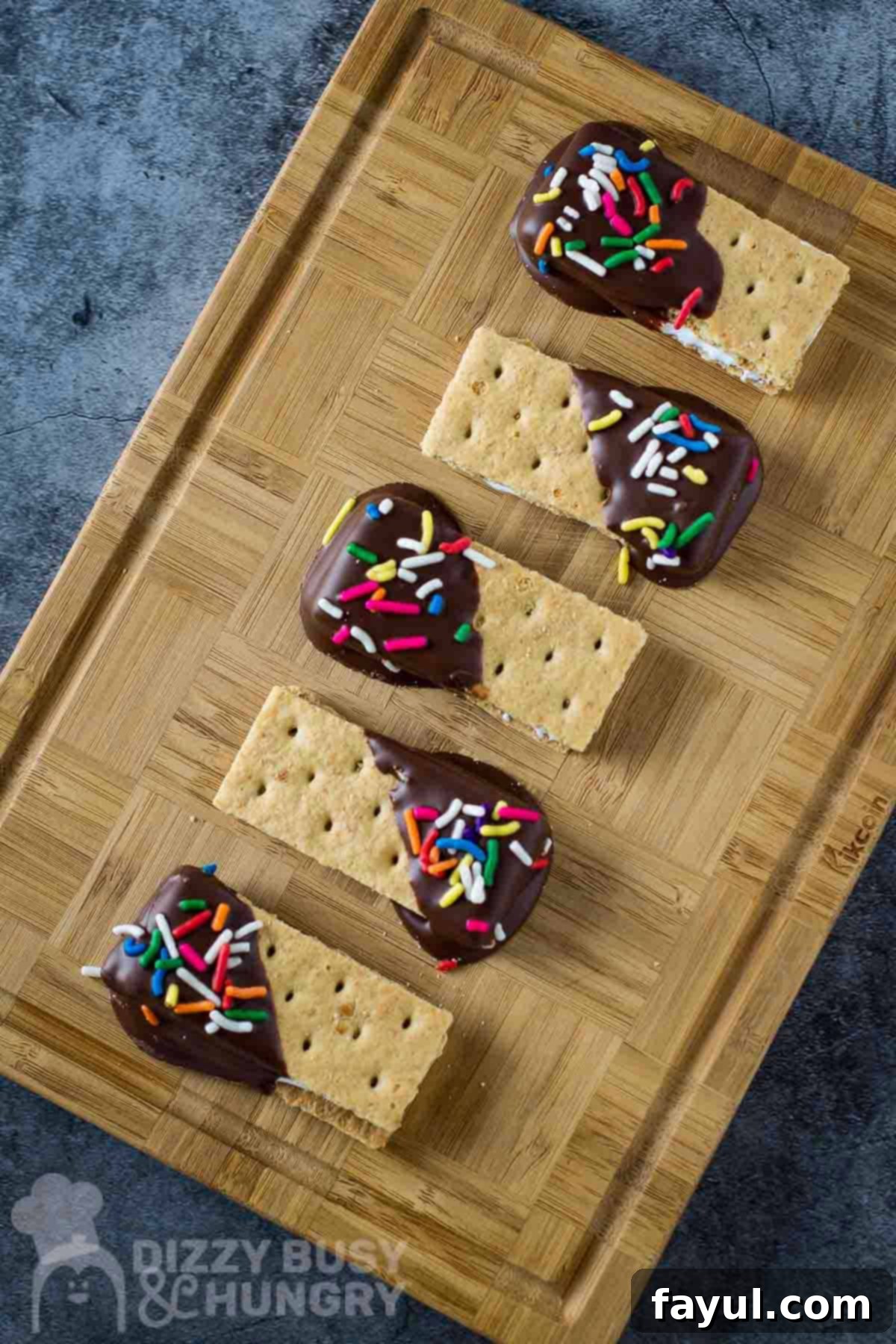 Overhead shot of s'mores bites in a row on a wooden cutting board.