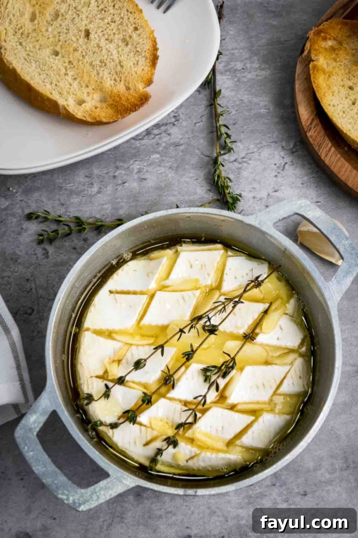 Overhead shot of baked brie garnished with fresh thyme in a small baking dish with more thyme sprigs on the side, ready to be served as an elegant appetizer.