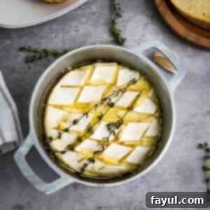 Overhead shot of baked brie garnished with fresh thyme in a small baking dish with more thyme sprigs on the side.