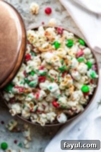 Overhead shot of Christmas Crunch mix in a copper tin on a white counter with napkin.