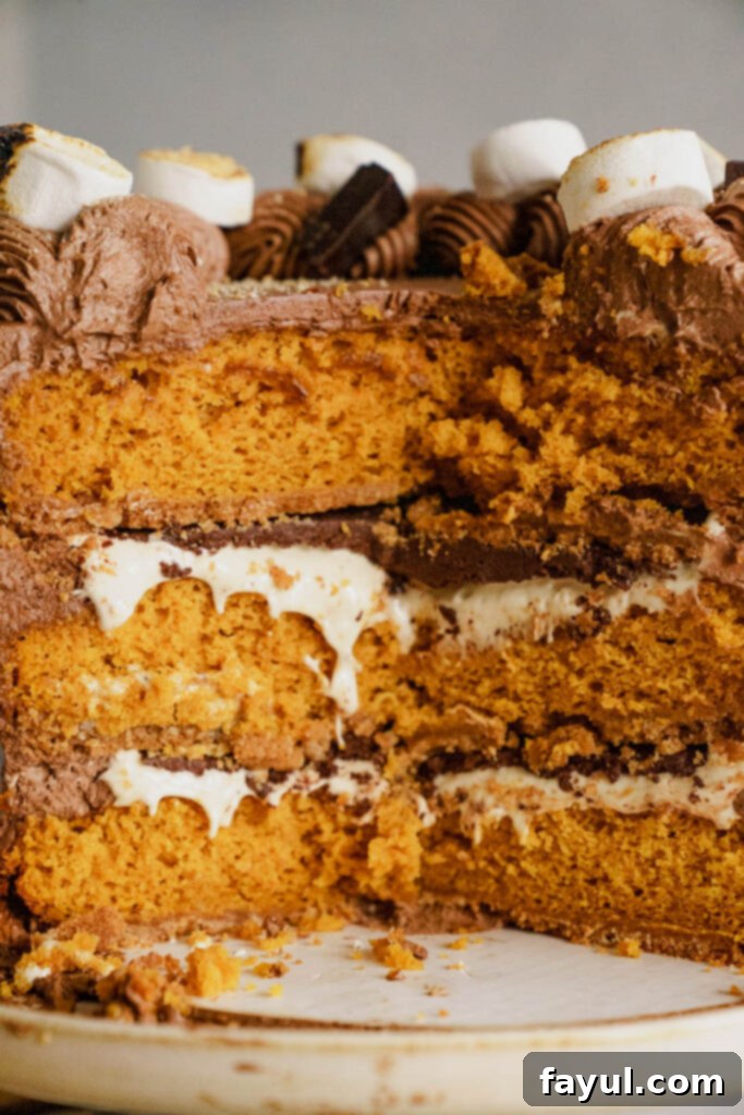 A slice of Pumpkin S'mores Cake on a white plate, showing all its delicious layers.