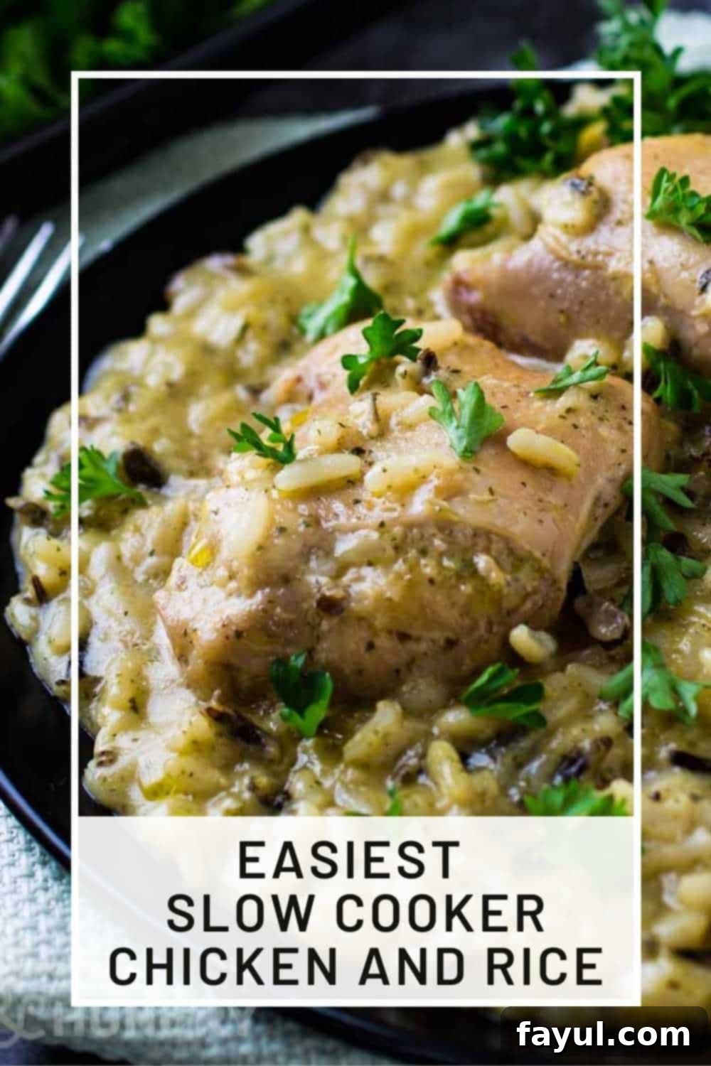 Side shot of slow cooker chicken and rice sprinkled with herbs on a black plate.