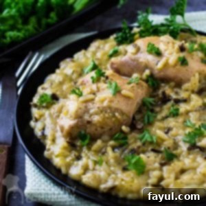 Side view of slow cooker chicken and wild rice on a black plate with a fork and knife on the side.