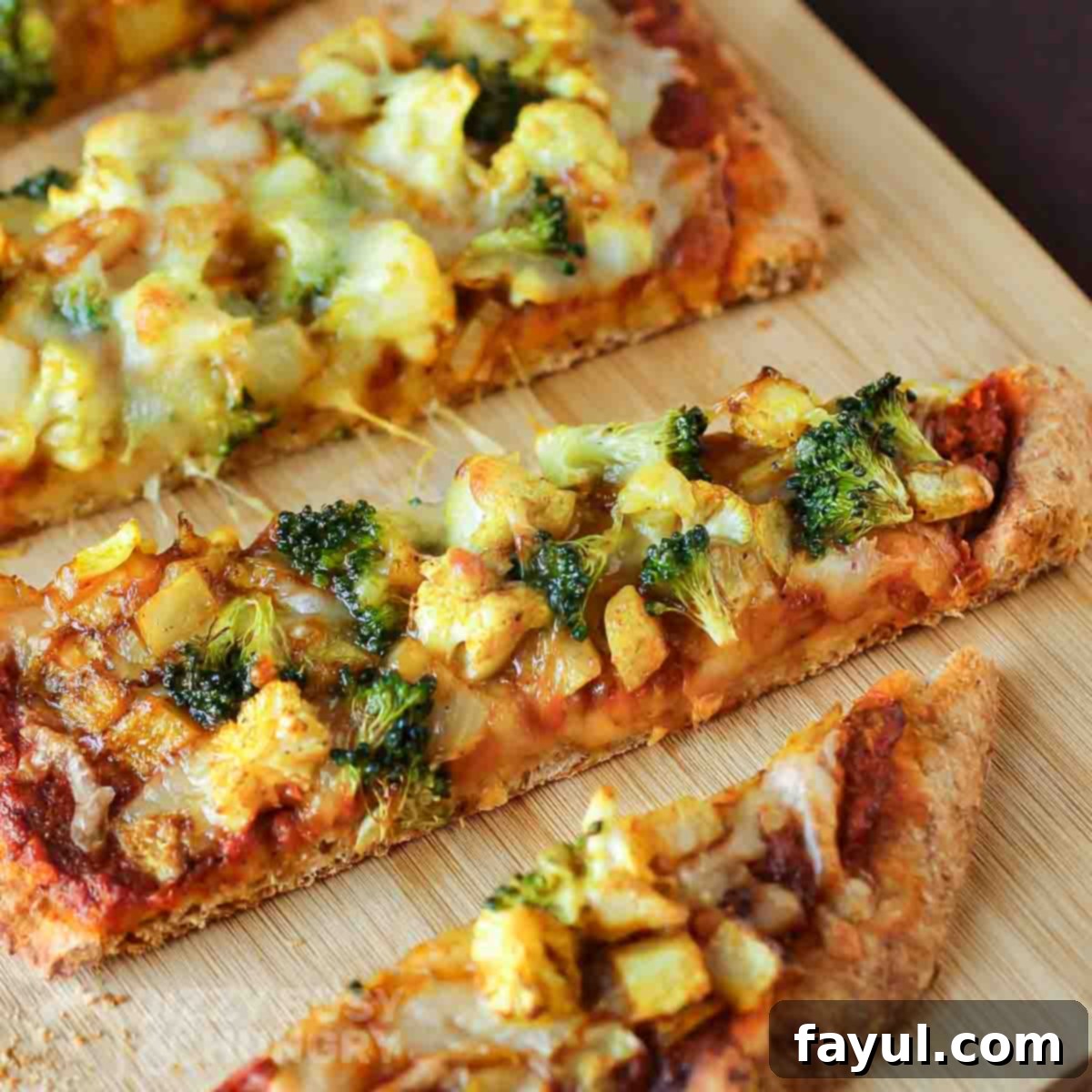 Close up shot of multiple slices of curry pizza on a wooden cutting board.