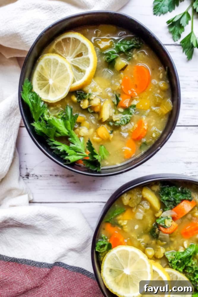 Overhead shot of two bowls of vibrant, hearty vegan lentil soup on a white counter with a white towel, garnished with fresh parsley and lemon slices.