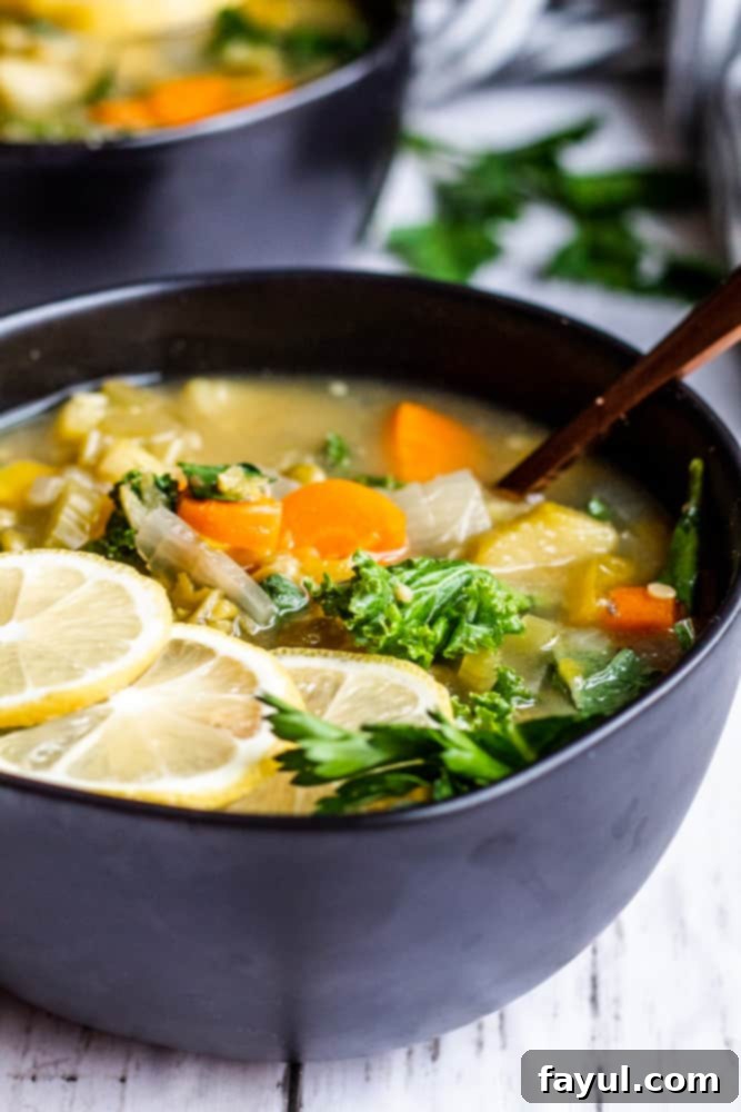 Two bowls of hot, steaming vegan lentil soup, garnished with fresh herbs, resting on a white counter.