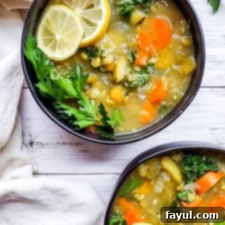 Overhead shot of a bowl of delicious vegan lentil soup in a black bowl on a white counter, garnished with herbs.