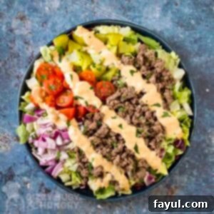 Overhead shot of big mac bowl drizzled with sauce and garnished with herbs in a blue bowl.