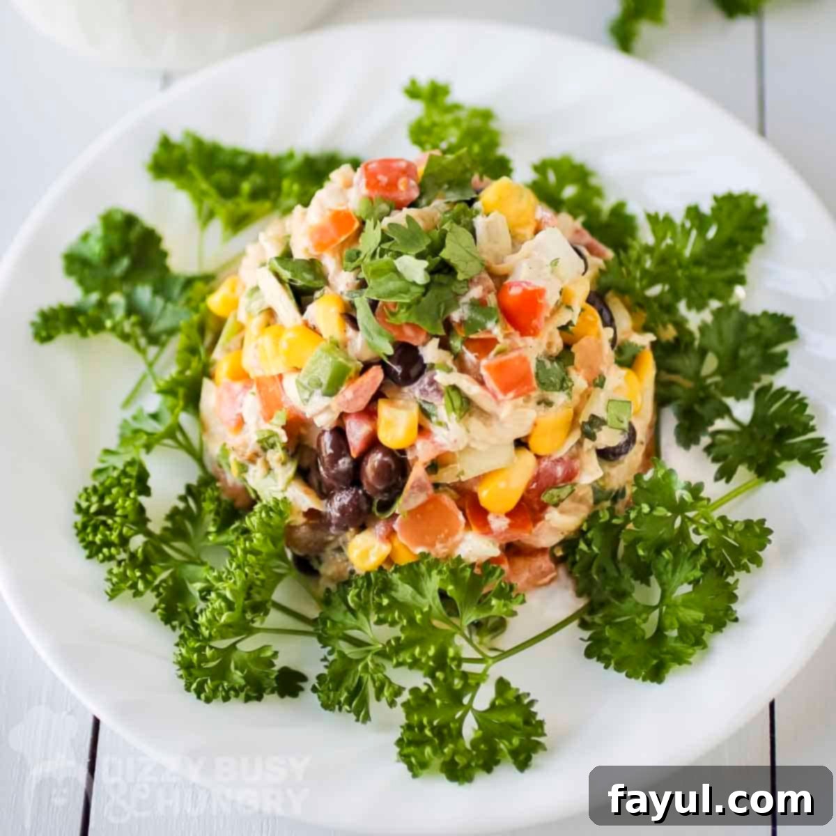 Overhead close up shot of southwest chicken salad garnished with fresh cilantro on a white plate with a fork on the side.