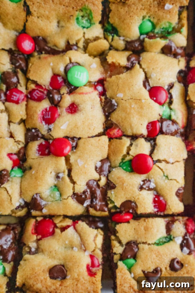 A cutting board with several Oreo M&M Blondies, some cut into squares