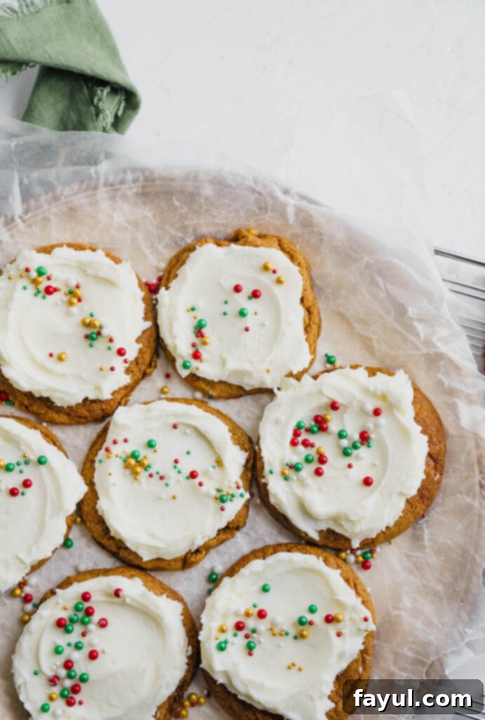 Frosted Gingerbread Cookies artfully arranged on a serving dish with a small bowl of sprinkles nearby.