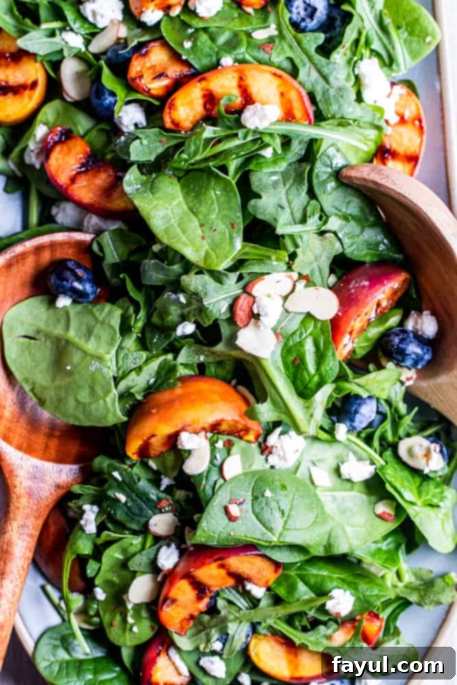 Salad on a blue platter with wood salad tossers. 