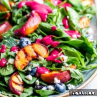 Grilled peach salad on a platter on a white counter.