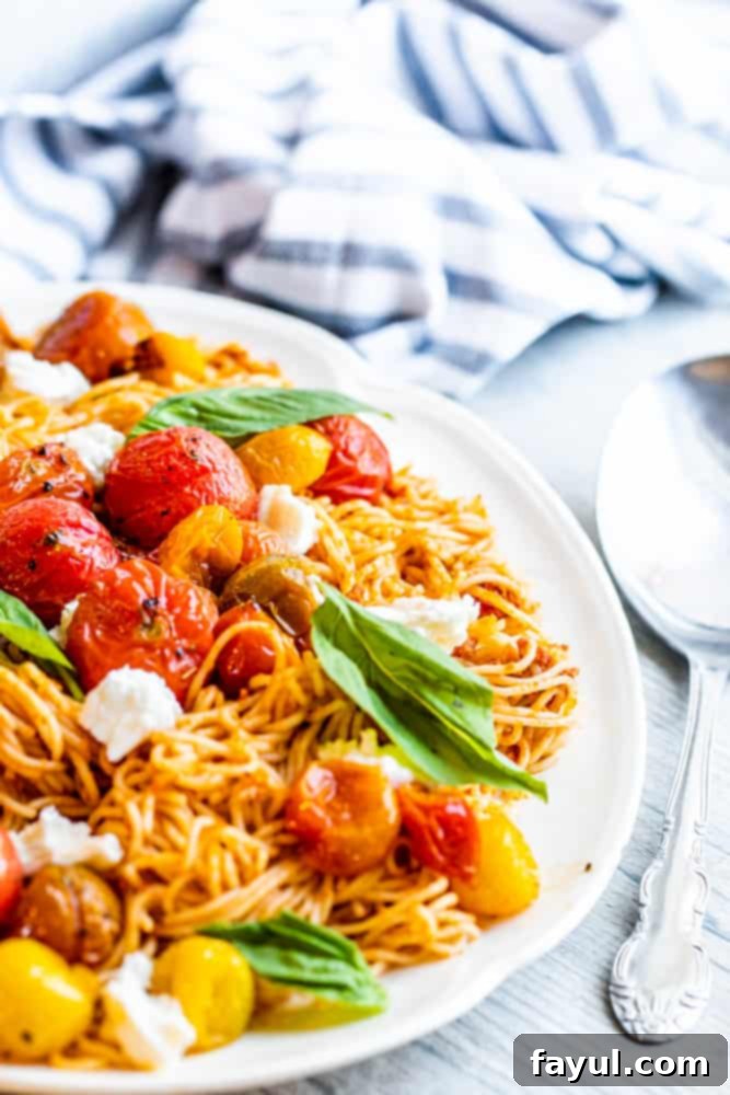 Delicious Red Pesto Pasta on a white serving platter, garnished with fresh basil, with a silver spoon ready to serve.