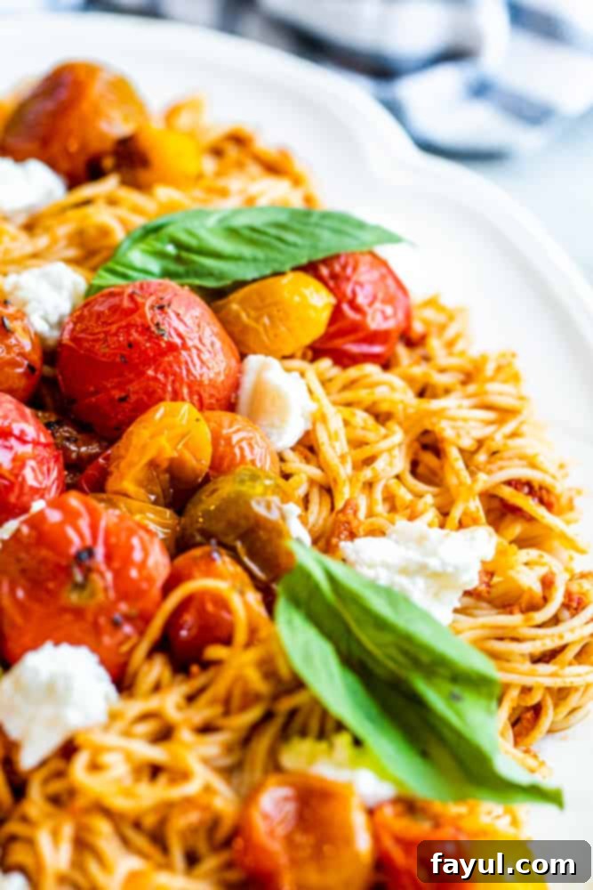 Close-up of vibrant red pesto pasta showcasing blistered roasted tomatoes, fresh mozzarella, and basil.