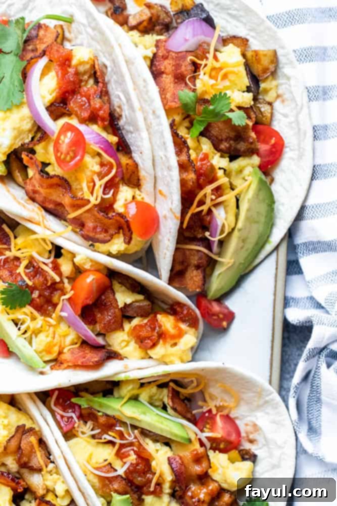 Overhead shot of five breakfast tacos artfully arranged on a white platter, set against a vibrant blue plate, showcasing crispy bacon, fluffy eggs, and golden potatoes.