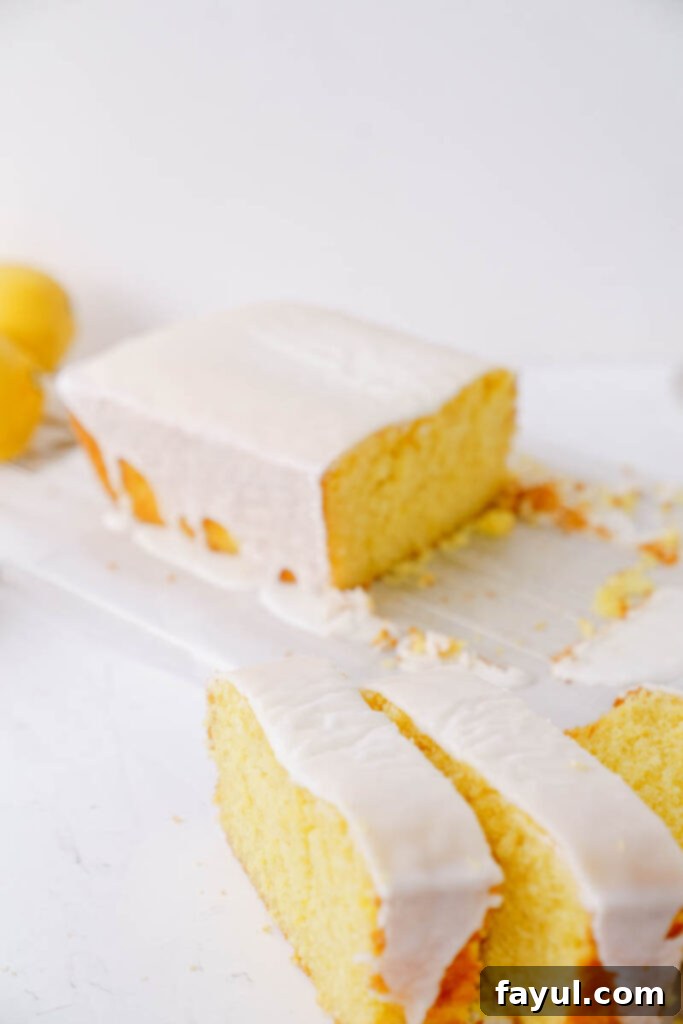 Overhead shot of a full lemon loaf cake, freshly baked and glazed, on a wooden board