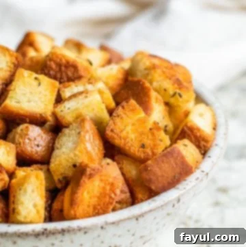 Croutons in a white bowl on a white counter.