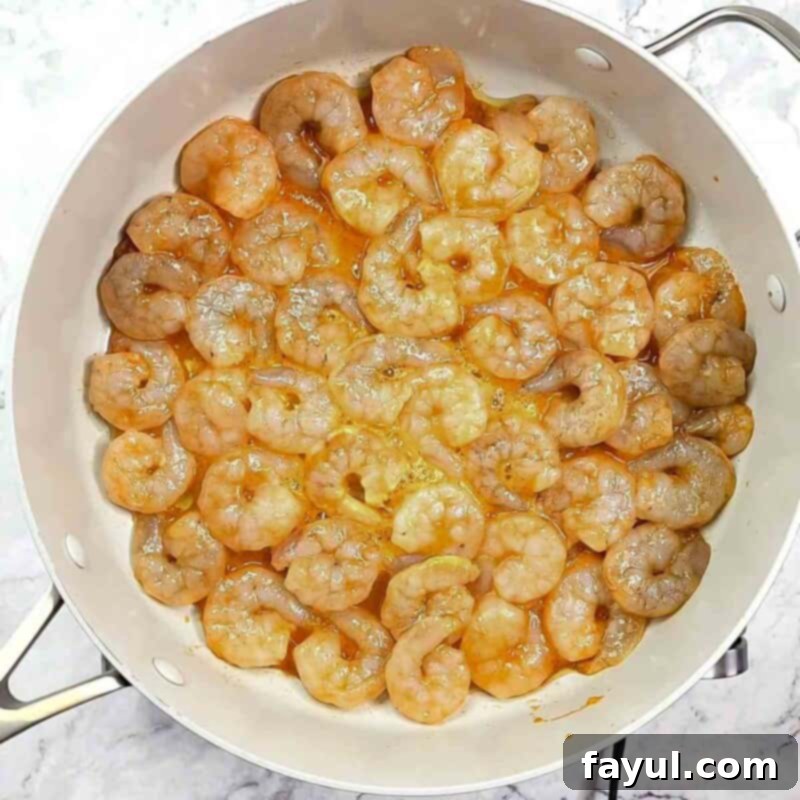 Overhead view of process shot 3 - heat olive oil in a skillet over medium high heat, then add the shrimp in a single layer.