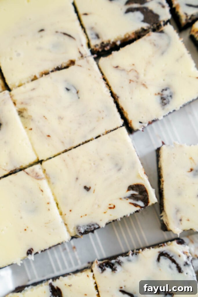 A half-eaten fudgy cheesecake brownie, revealing the gooey chocolate interior and the creamy cheesecake layer.