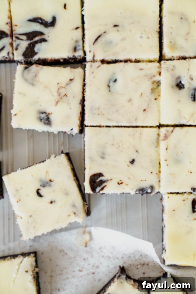 A tray of freshly baked cheesecake brownies, glistening with a rich chocolate and cream cheese swirl, ready to be chilled and cut.