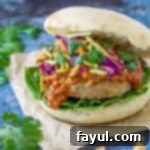 Side angle view of Thai turkey burger on a bun topped with peanut sauce and Asian-style slaw
