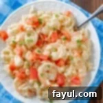 Overhead shot of creamy shrimp and rice garnished with chives on a white plate with a fork and a blue cloth on the side.