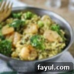 Side shot of shrimp curry in a metal bowl on a white and green cloth with a fork on the side.