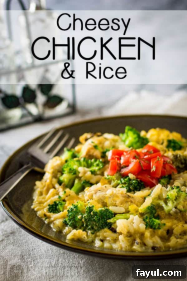 Side view of cheesy chicken and rice in a brown dish topped with chopped tomato.