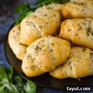 Side angled shot of zucchini cheese bites stacked on a black plate with herbs on the side.