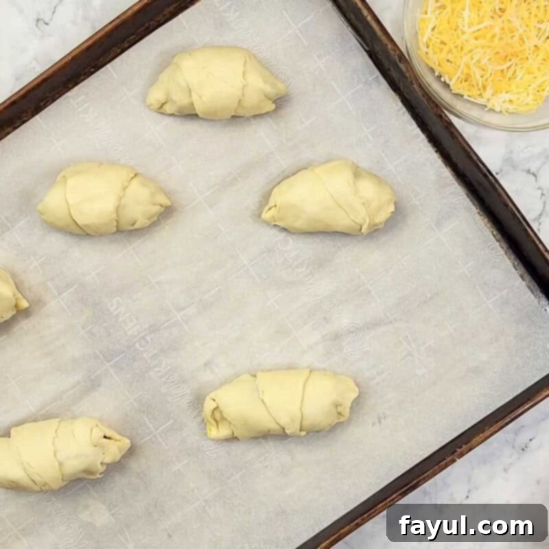 Overhead view of process shot 6 - roll up the crescent roll dough, pinching the sides as you go to seal it, ready for baking.