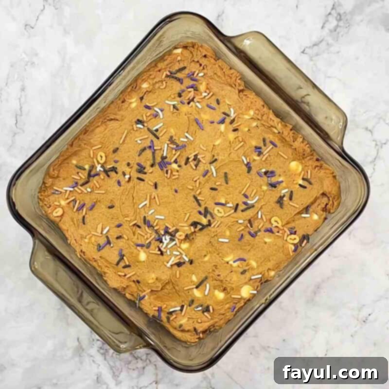 Overhead view of process shot 3 - pour mixture into baking pan coated with non-stick cooking spray and distribute the fall-themed sprinkles on top, if desired.