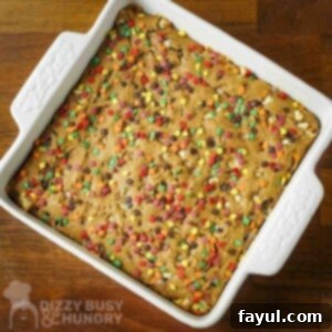 Overhead shot of spice cake with fall-themed sprinkles in a white square baking dish on a wooden surface.
