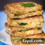 Close up side view of four halves of zingy shrimp grilled cheese stacked on each other garnished with fresh herbs on a white plate on a white surface.
